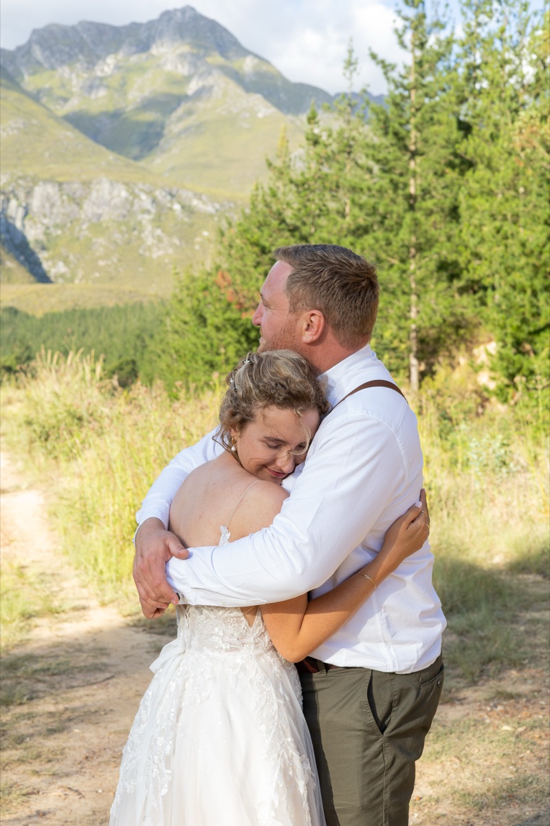 A bride and groom holding each other on a mountain path