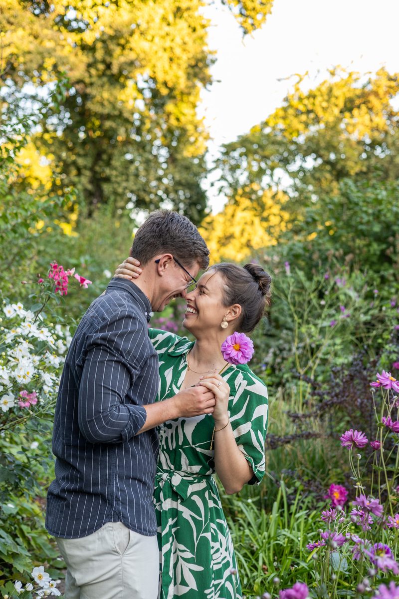 A couple laughing together among pink dahlias in a summer garden