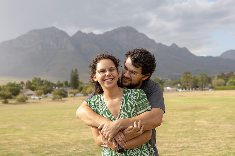 A couple embracing on a lawn with the mountain behind them