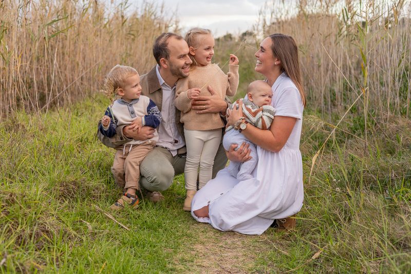 A family with three young children among tall golden reeds