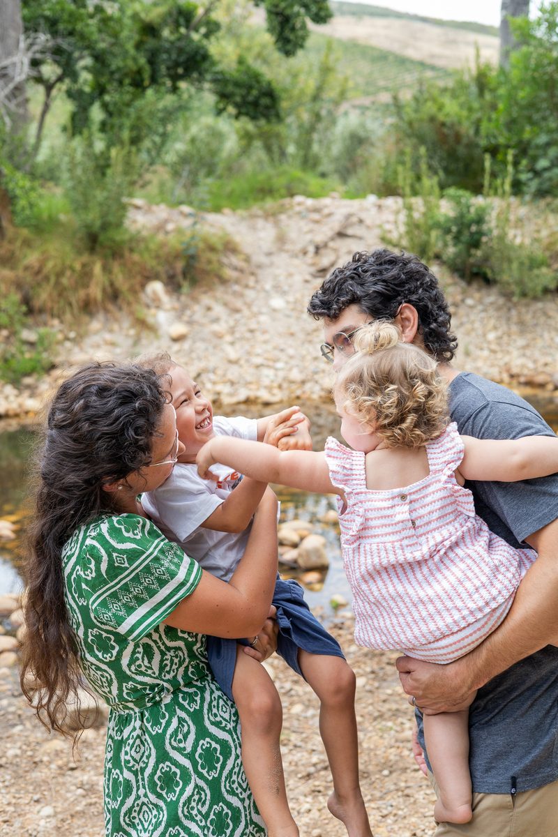 Parents lifting their two small children beside a river